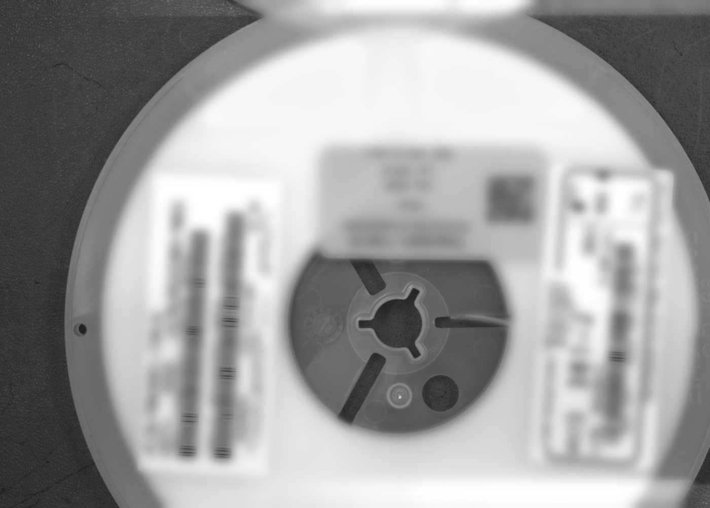 Component reel with several stacked labels including non-English text; label text blurred